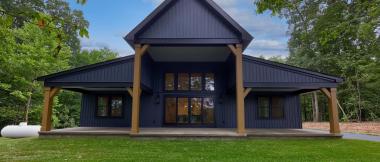 exterior of navy blue modern farmhouse with black framed windows and rustic wood columns