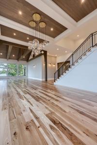 great room in modern farmhouse style with globe bulb chandelier, dark wood panel tray ceilings, and hardwood floor