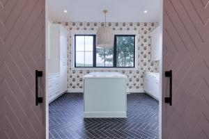 laundry room with island, wallpaper accent wall, and dark tile floor in a herringbone pattern