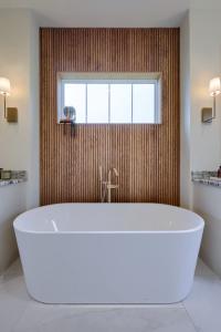 soaking tub in front of vertical wood slat accent wall with window