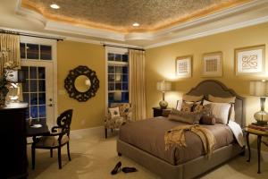 bedroom with tray ceiling and featuring rope lighting, trim, and decorative wallpaper accent