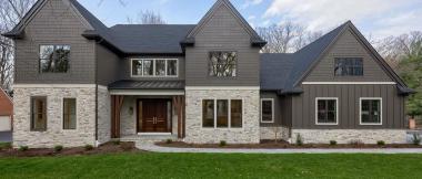 exterior of custom home with dark siding and light stone siding